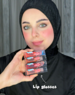 امرأة محجبة تمسك مجموعة Lip Gloss من Safira بدرجات ألوان مختلفة مع لمعة ناعمة ومظهر شفاه صحي